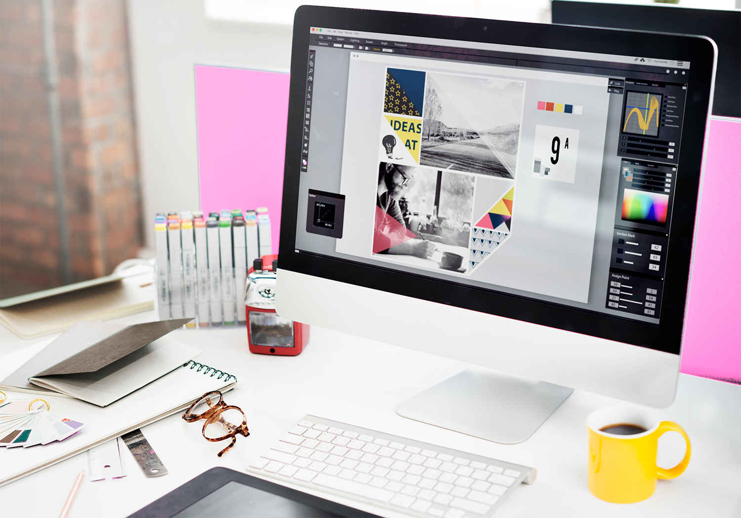 Bureau de graphiste avec un moodboard en cours sur écran et des outils de création visuelle.